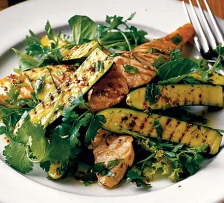 Griddled courgette halves and salmon strips on a bed of herb salad