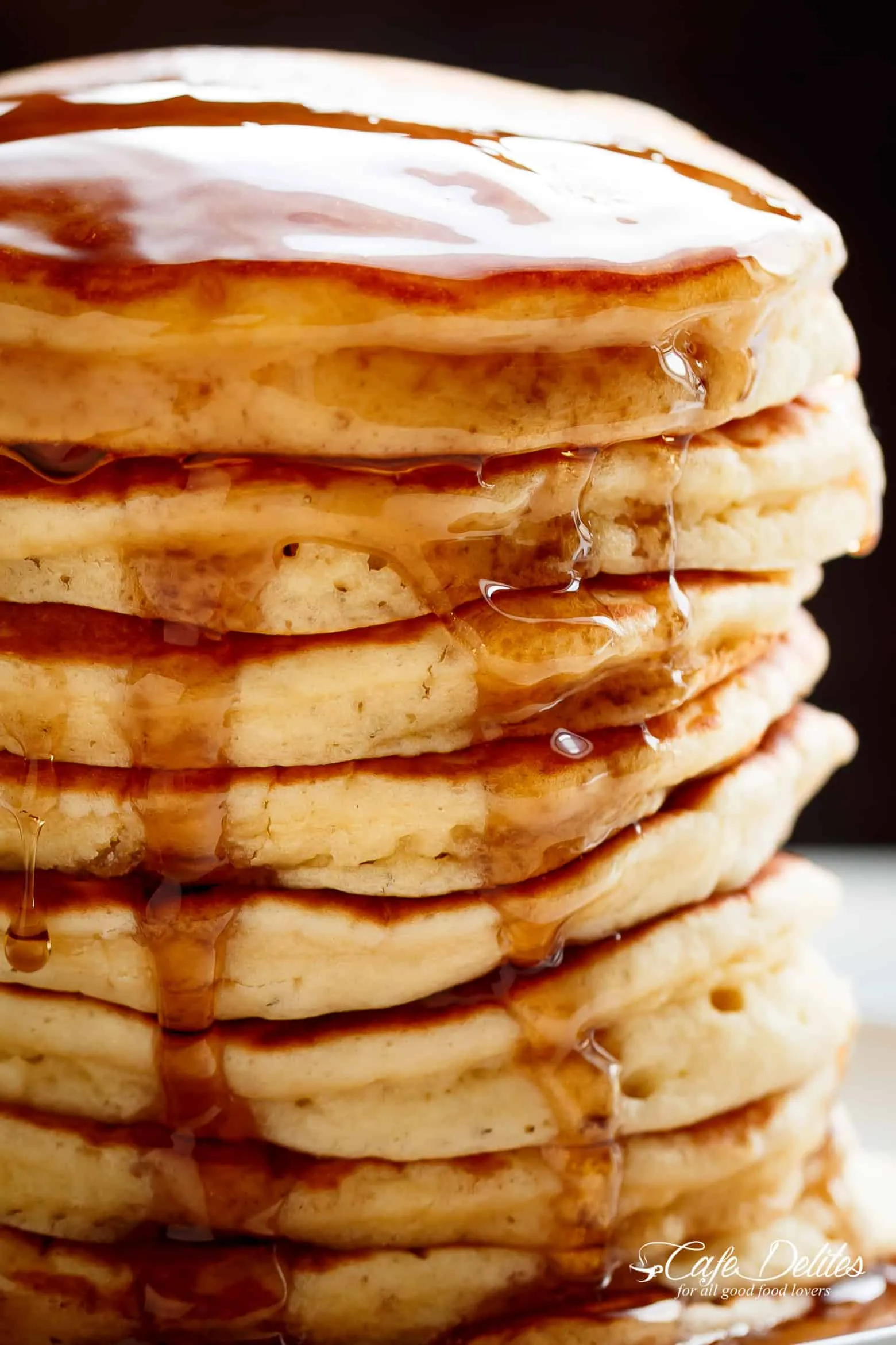 A tall stack of fluffy pancakes dripping with syrup